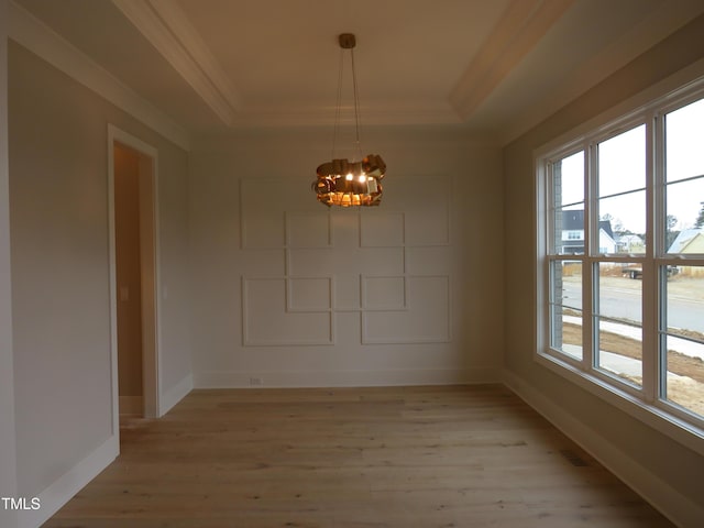 unfurnished dining area featuring an inviting chandelier, light hardwood / wood-style floors, and a raised ceiling