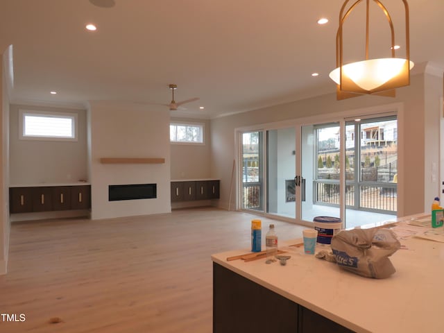 kitchen featuring a fireplace, plenty of natural light, ceiling fan, and light wood-type flooring