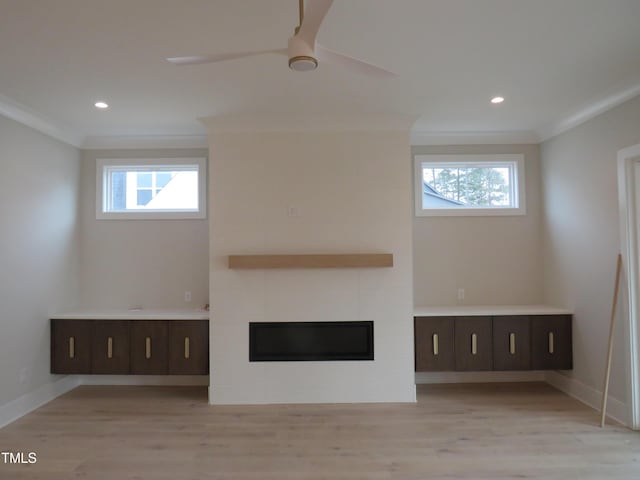 unfurnished living room with ceiling fan, ornamental molding, a fireplace, and light hardwood / wood-style flooring