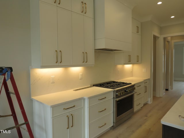 kitchen with white cabinetry, high end range, light hardwood / wood-style floors, and wall chimney range hood