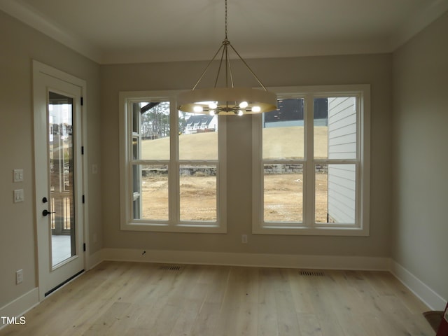 unfurnished dining area featuring an inviting chandelier and light hardwood / wood-style flooring