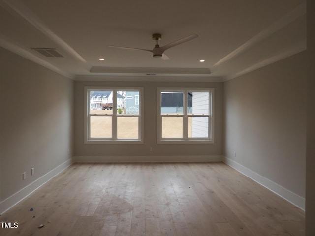 empty room with ceiling fan, a raised ceiling, and light hardwood / wood-style floors