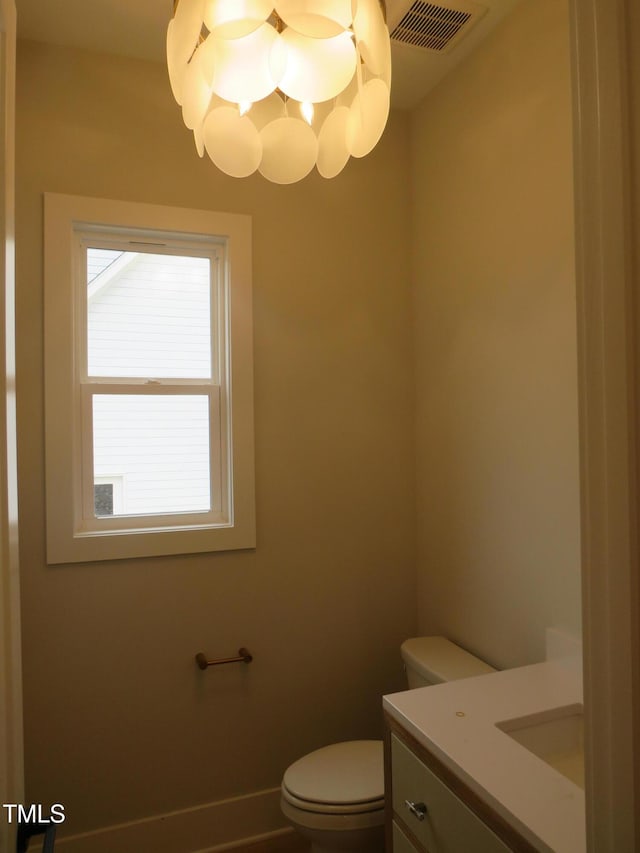 bathroom featuring vanity, an inviting chandelier, and toilet