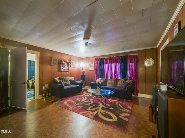 living room featuring crown molding, wooden walls, ceiling fan, and dark parquet flooring