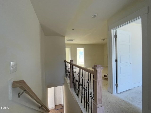 hall with an upstairs landing and light carpet
