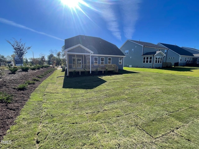 back of house with a deck, a yard, and a sunroom
