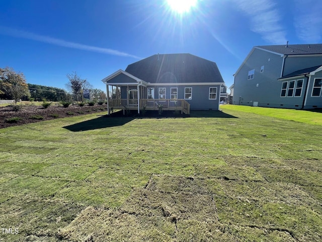 rear view of property featuring a yard and a wooden deck