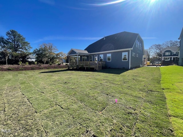 back of property featuring a deck, a yard, a sunroom, and stairs