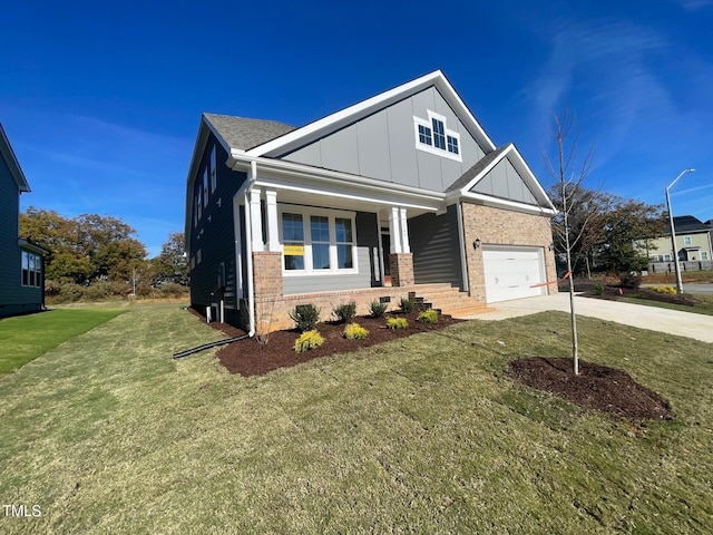 craftsman-style house with board and batten siding, concrete driveway, brick siding, covered porch, and a front yard
