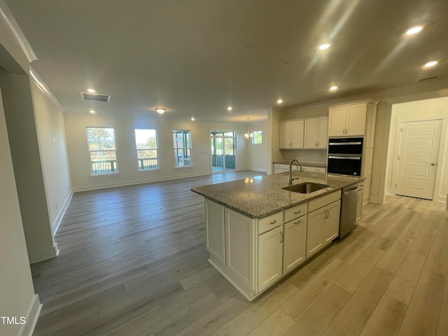 kitchen with light stone countertops, a center island with sink, light hardwood / wood-style flooring, dishwasher, and white cabinetry