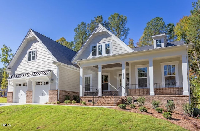 view of front of house with covered porch, a front yard, and a garage