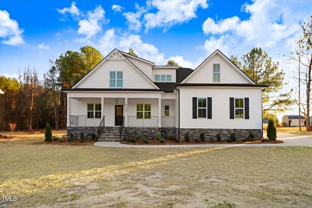 modern farmhouse with a front yard and covered porch