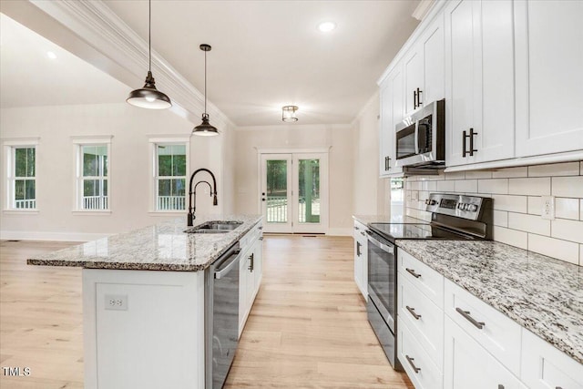 kitchen with white cabinets, an island with sink, hanging light fixtures, light hardwood / wood-style flooring, and stainless steel appliances