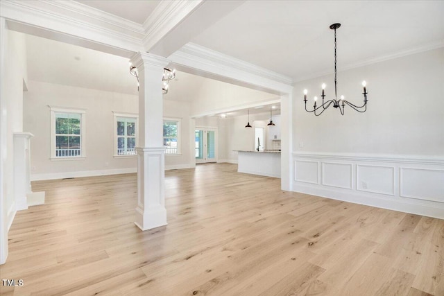 interior space featuring crown molding, an inviting chandelier, light hardwood / wood-style flooring, and ornate columns