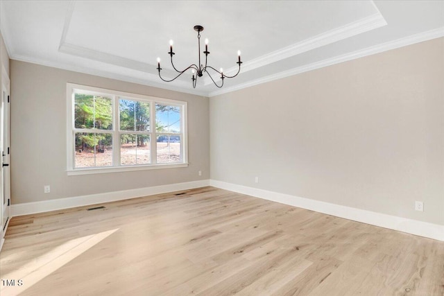 interior space featuring a notable chandelier, light wood-type flooring, a tray ceiling, and crown molding