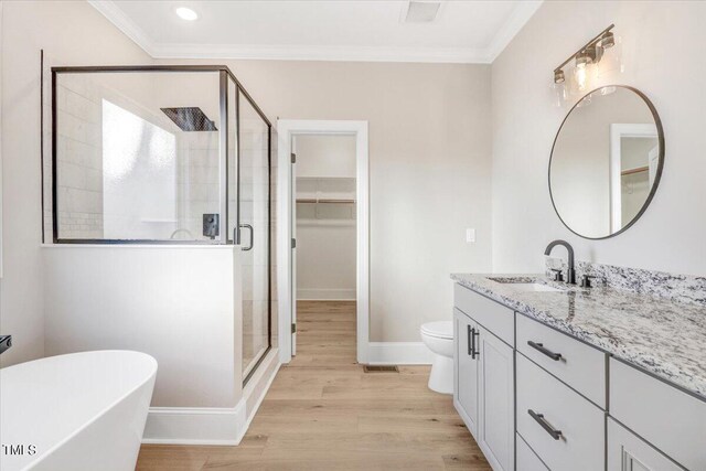 full bathroom with vanity, wood-type flooring, separate shower and tub, ornamental molding, and toilet