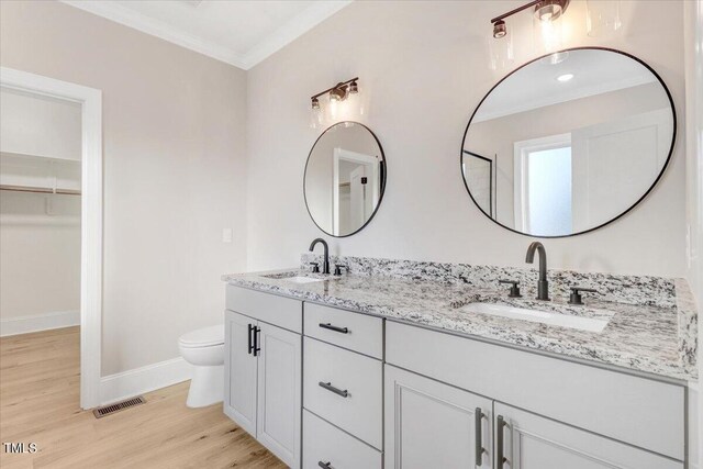 bathroom with crown molding, wood-type flooring, vanity, and toilet