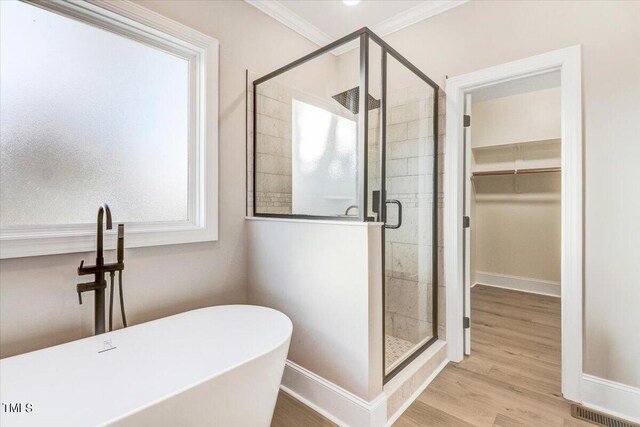 bathroom featuring ornamental molding, hardwood / wood-style floors, and plus walk in shower