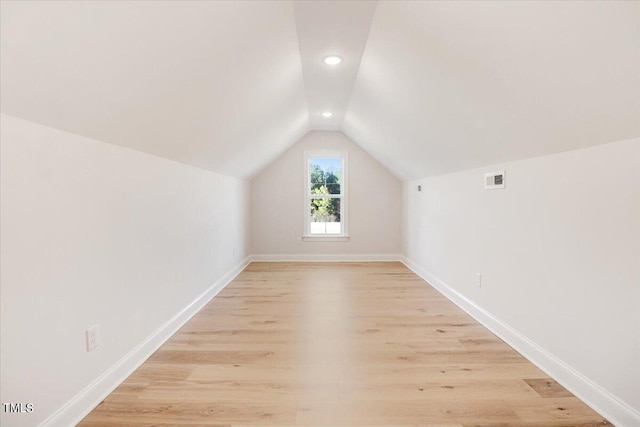 additional living space with vaulted ceiling and light hardwood / wood-style floors