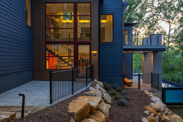 exterior entry at dusk with a balcony and a patio