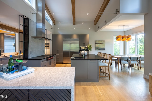 kitchen with gray cabinetry, decorative light fixtures, stainless steel refrigerator, a center island, and light wood-type flooring