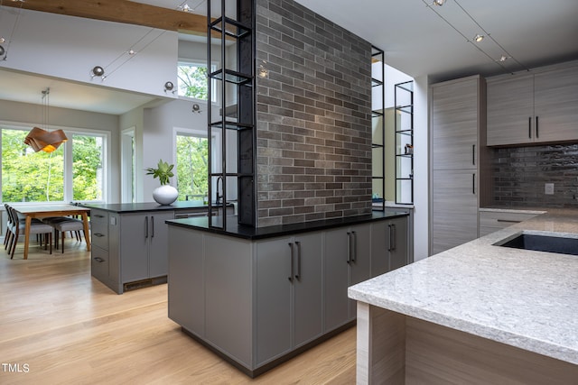 kitchen with gray cabinetry, a kitchen island, pendant lighting, and light hardwood / wood-style flooring