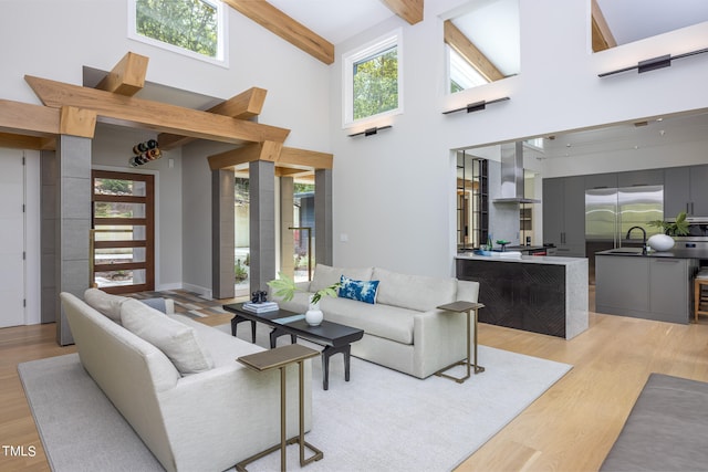 living room with high vaulted ceiling, light wood-type flooring, and plenty of natural light