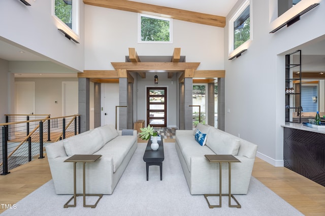 living room featuring light hardwood / wood-style floors, beamed ceiling, and high vaulted ceiling