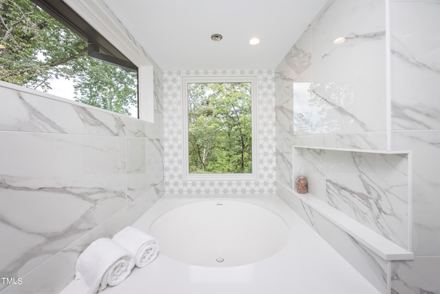 bathroom featuring a bath and tile walls