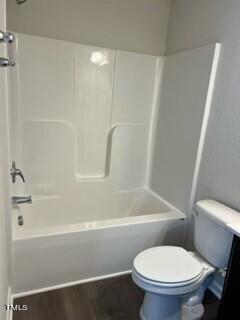 bathroom featuring shower / bathing tub combination, hardwood / wood-style floors, and toilet