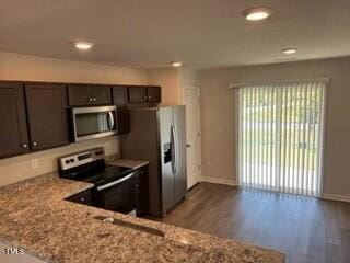 kitchen featuring dark brown cabinets, light stone countertops, appliances with stainless steel finishes, and light hardwood / wood-style floors