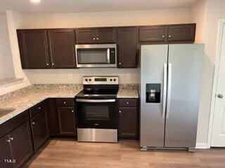 kitchen featuring dark brown cabinets, appliances with stainless steel finishes, and light wood-type flooring