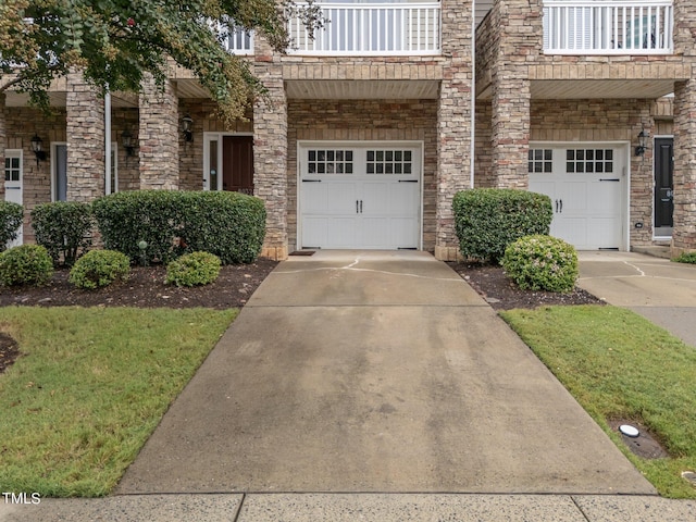 townhome / multi-family property featuring a balcony, a front yard, and a garage