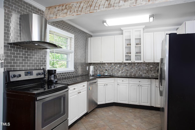 kitchen with decorative backsplash, appliances with stainless steel finishes, wall chimney range hood, and white cabinetry