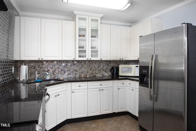 kitchen featuring white cabinets, stainless steel refrigerator with ice dispenser, dark tile patterned flooring, and sink