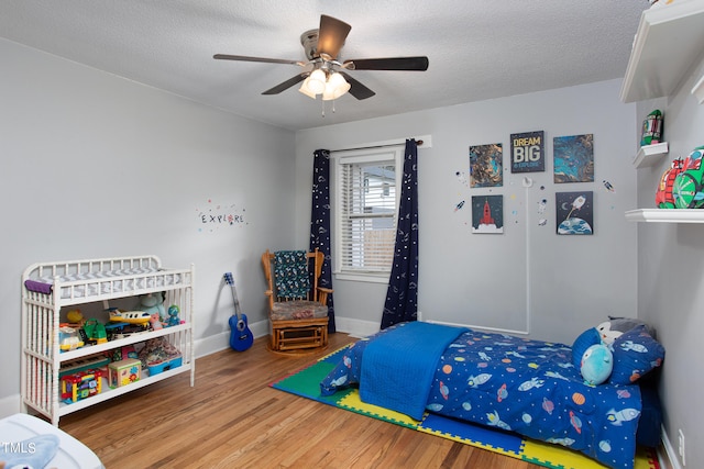 bedroom with a textured ceiling, wood-type flooring, and ceiling fan