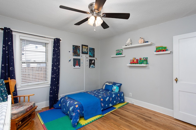 bedroom featuring ceiling fan, hardwood / wood-style floors, and a textured ceiling