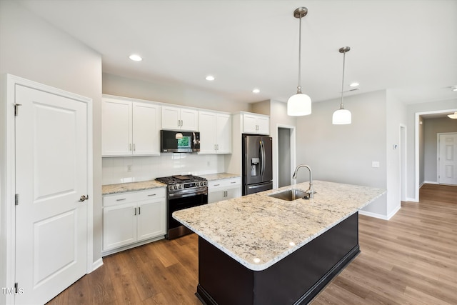 kitchen with stainless steel appliances, white cabinetry, a center island with sink, and sink