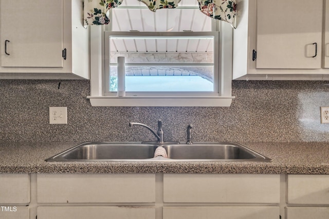 kitchen with white cabinets, sink, and tasteful backsplash