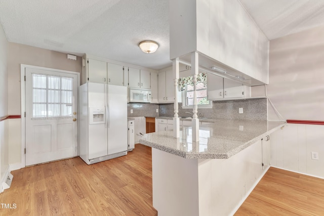 kitchen featuring kitchen peninsula, white appliances, a textured ceiling, light hardwood / wood-style flooring, and white cabinetry