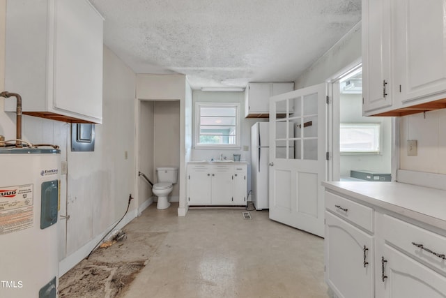 kitchen featuring white cabinets, water heater, white fridge, and a textured ceiling