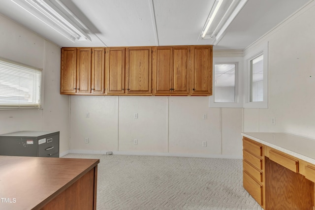 kitchen with ornamental molding and light carpet