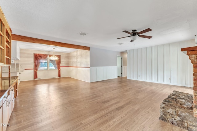 unfurnished living room featuring light hardwood / wood-style floors, ceiling fan, and a textured ceiling