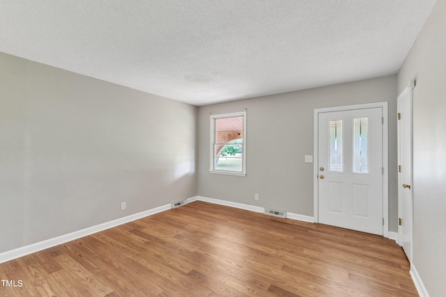 entryway with light wood-type flooring and a textured ceiling