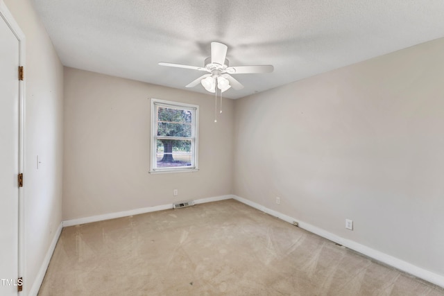 spare room featuring a textured ceiling, light carpet, and ceiling fan