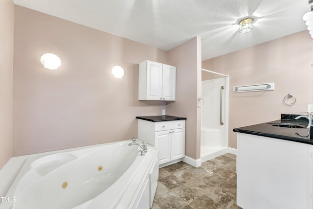 bathroom with a textured ceiling, vanity, and separate shower and tub