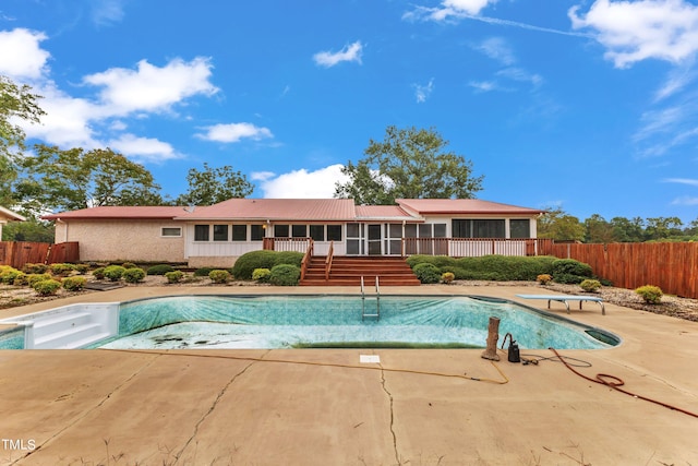 view of swimming pool featuring a sunroom, a patio area, and a diving board