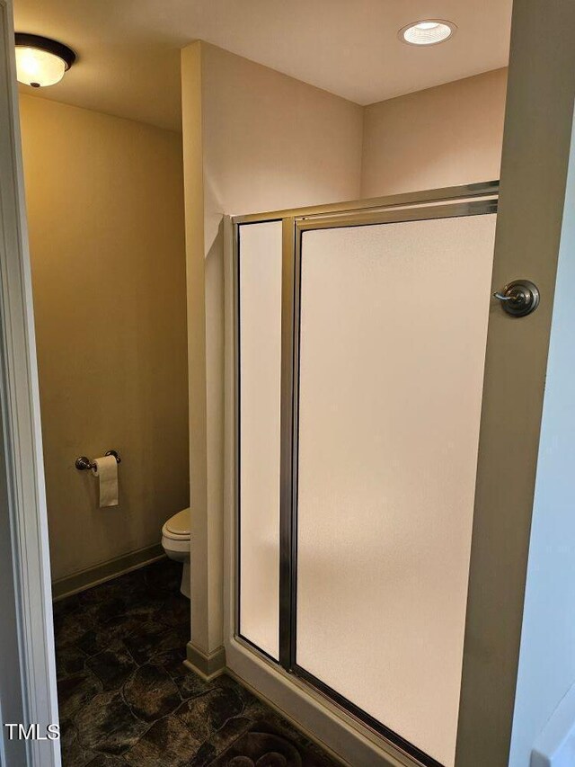 bathroom with toilet and a shower with shower door