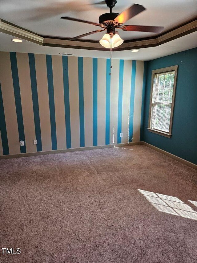 carpeted empty room with ornamental molding, ceiling fan, and a raised ceiling