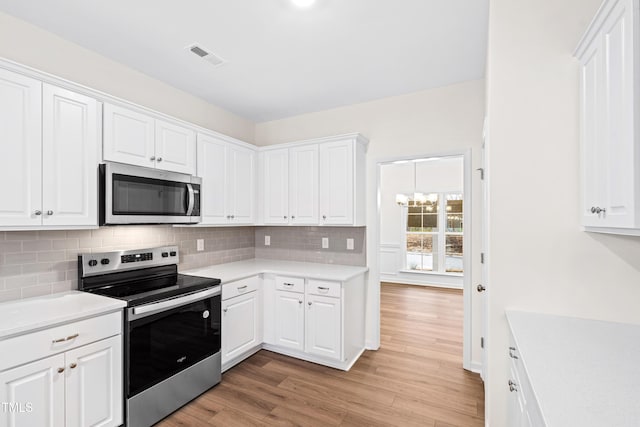 kitchen featuring tasteful backsplash, stainless steel appliances, light hardwood / wood-style flooring, and white cabinets